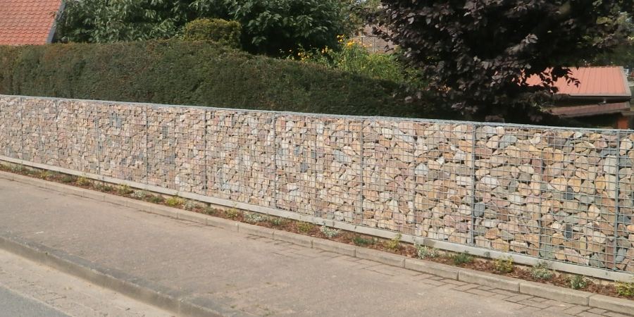 Een lage schanskorven schutting gevuld met maaskeien